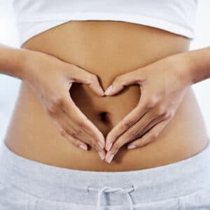 Frau formt mit Ihren Händen ein Herz auf ihrem Bauch
